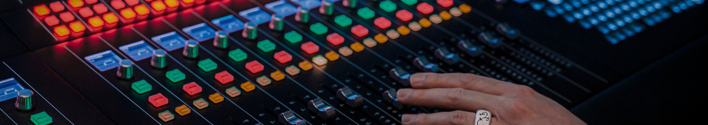 Hands on the illuminated faders of the Fairlight console